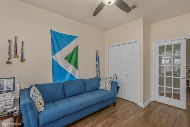 living room featuring visible vents, baseboards, wood finished floors, and a ceiling fan