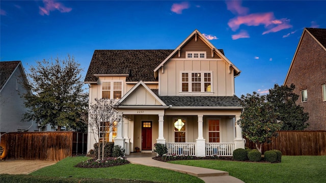 craftsman-style house featuring fence, roof with shingles, a porch, a lawn, and board and batten siding