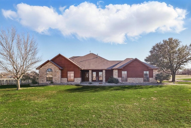 rear view of house featuring stone siding and a lawn