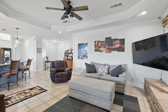 living room with a raised ceiling, light tile patterned floors, crown molding, and visible vents