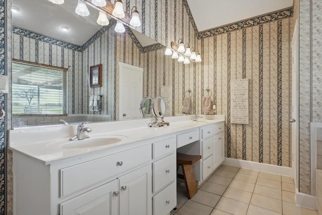 full bath with a sink, wallpapered walls, tile patterned flooring, double vanity, and baseboards