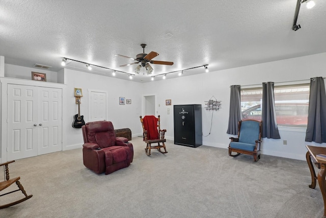 living area with ceiling fan, track lighting, carpet floors, and a textured ceiling