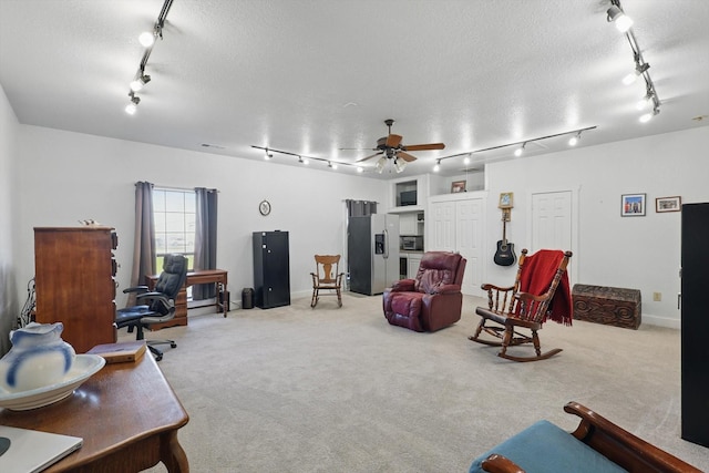 interior space featuring ceiling fan, light carpet, rail lighting, and a textured ceiling