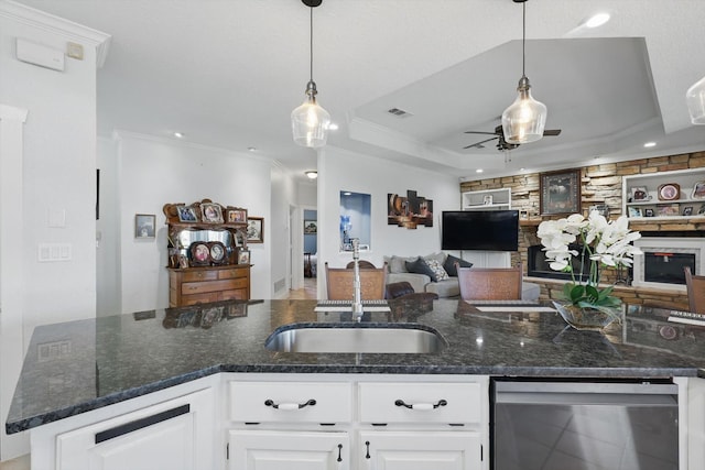 kitchen featuring a tray ceiling, ornamental molding, a sink, stainless steel dishwasher, and open floor plan