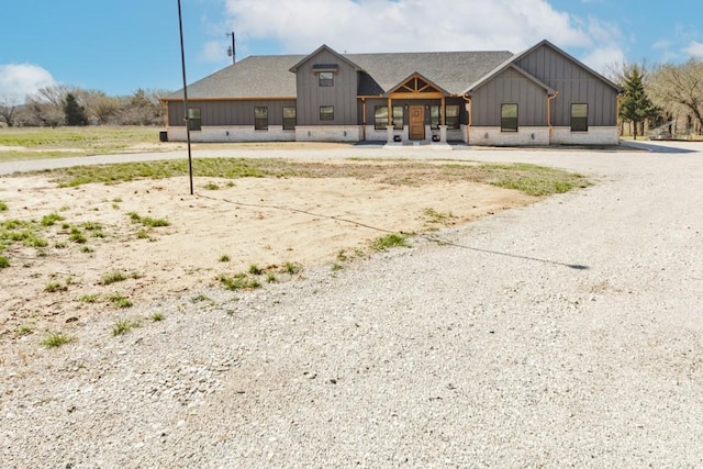 view of front of home featuring board and batten siding, driveway, and roof with shingles