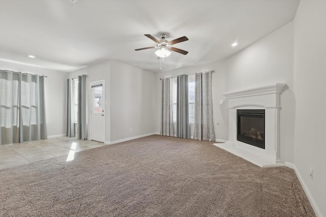 unfurnished living room featuring ceiling fan, baseboards, carpet, and a glass covered fireplace