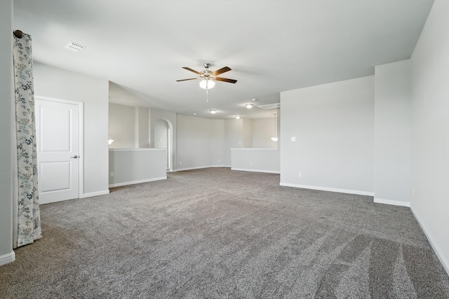 carpeted empty room with visible vents, baseboards, arched walkways, and ceiling fan