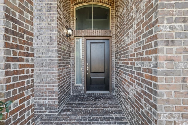 entrance to property featuring brick siding