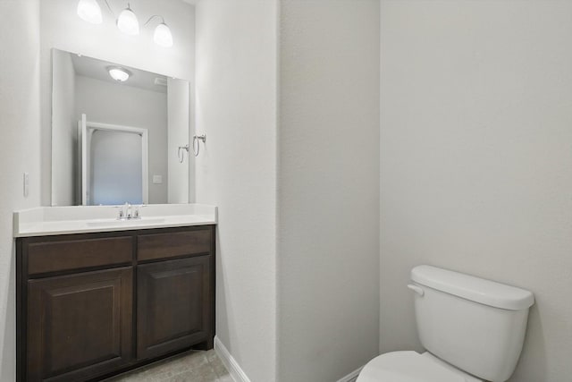 bathroom with baseboards, toilet, and vanity