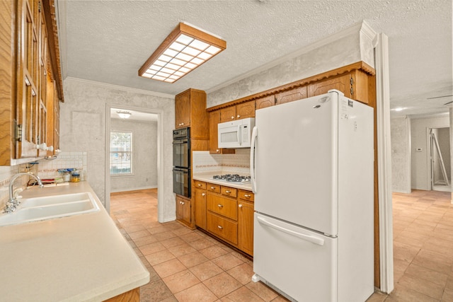 kitchen with white appliances, light countertops, brown cabinets, and a sink