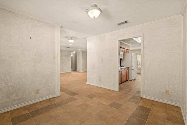 empty room with visible vents, crown molding, and baseboards