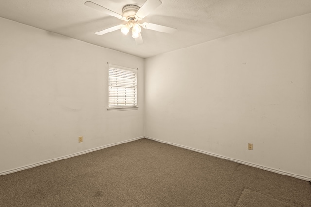 spare room featuring baseboards, ceiling fan, and dark carpet