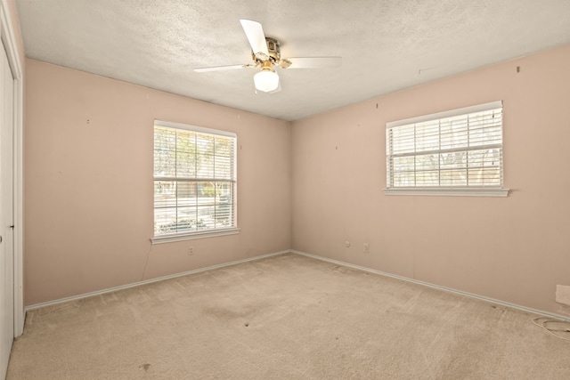 carpeted empty room with baseboards, a textured ceiling, and ceiling fan