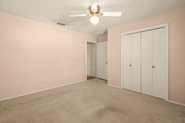 unfurnished bedroom featuring light colored carpet, visible vents, a closet, and ceiling fan