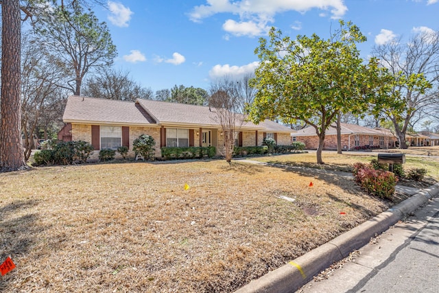 ranch-style house featuring a front lawn, brick siding, and roof with shingles