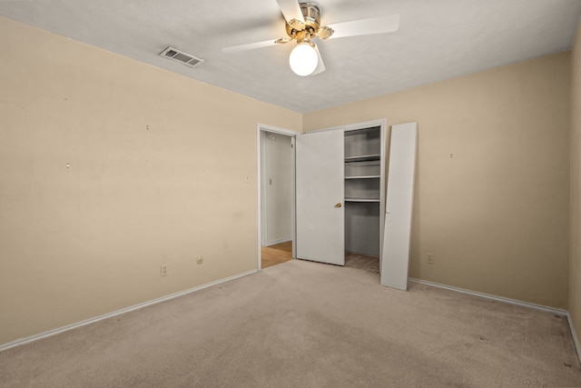 unfurnished bedroom with visible vents, a closet, baseboards, light colored carpet, and ceiling fan