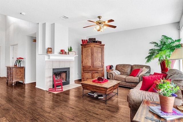 living area with visible vents, baseboards, ceiling fan, a fireplace, and wood finished floors