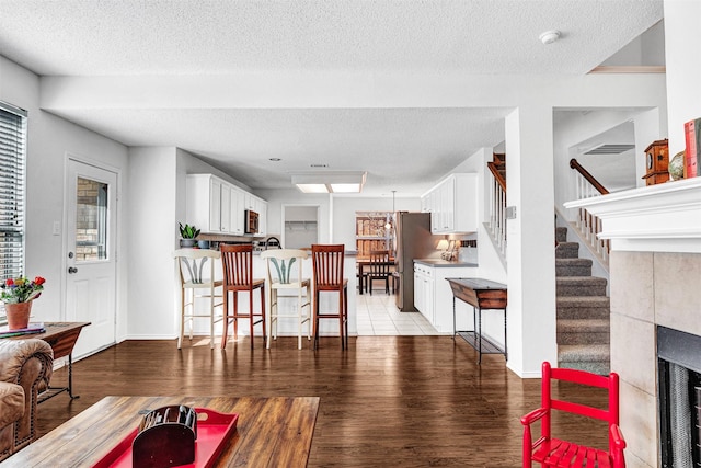 living room with light wood-style flooring, a textured ceiling, stairs, and baseboards