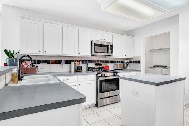 kitchen with a sink, backsplash, appliances with stainless steel finishes, white cabinets, and washing machine and clothes dryer