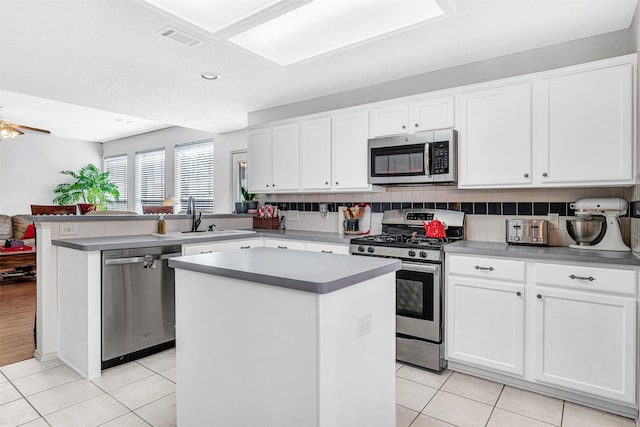 kitchen with visible vents, tasteful backsplash, a center island, appliances with stainless steel finishes, and a peninsula