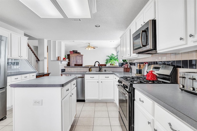 kitchen featuring light tile patterned floors, a peninsula, stainless steel appliances, and a sink