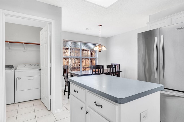 kitchen with a kitchen island, light tile patterned floors, freestanding refrigerator, a notable chandelier, and white cabinets