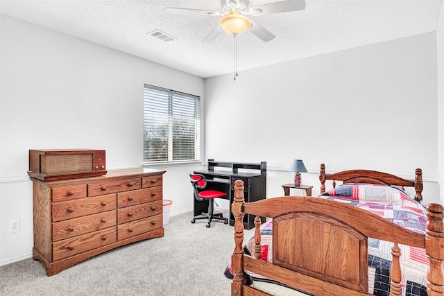 carpeted bedroom with visible vents, a textured ceiling, baseboards, and a ceiling fan