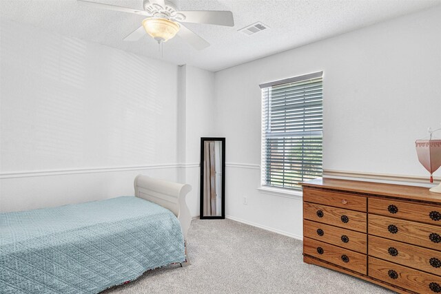 bedroom featuring a ceiling fan, baseboards, visible vents, a textured ceiling, and light colored carpet