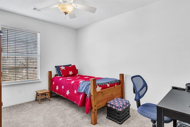 carpeted bedroom with visible vents, baseboards, a textured ceiling, and ceiling fan