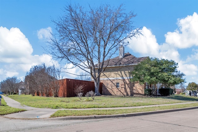 view of property exterior with a yard, brick siding, and a chimney