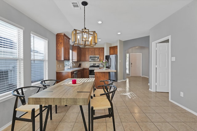 dining space featuring visible vents, arched walkways, light tile patterned flooring, baseboards, and a chandelier