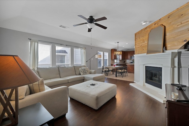 living room with dark wood finished floors, a glass covered fireplace, visible vents, and a wealth of natural light