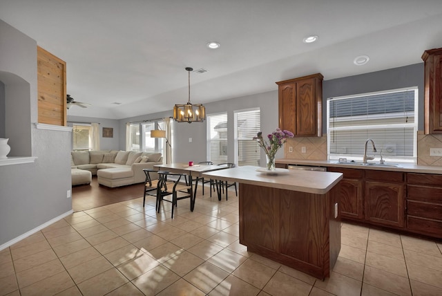 kitchen featuring tasteful backsplash, open floor plan, light countertops, light tile patterned floors, and a sink