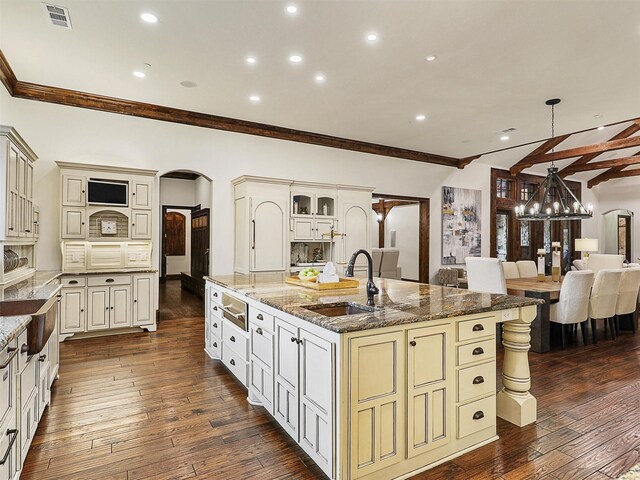 kitchen with a sink, visible vents, arched walkways, and cream cabinetry