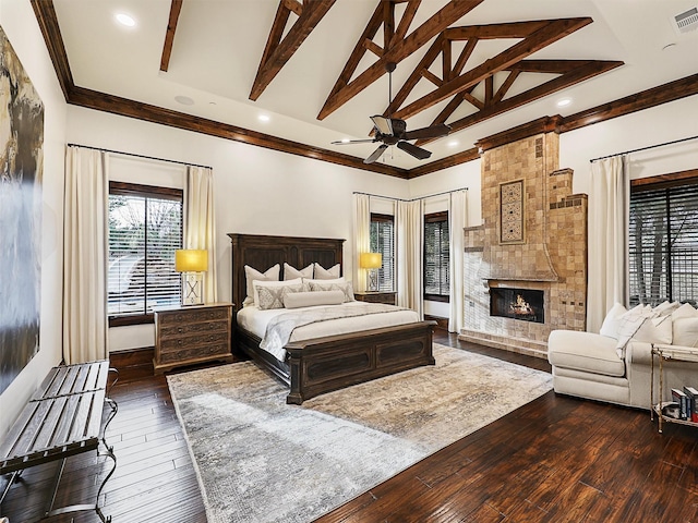 bedroom featuring dark wood-style floors, visible vents, beam ceiling, ornamental molding, and a large fireplace