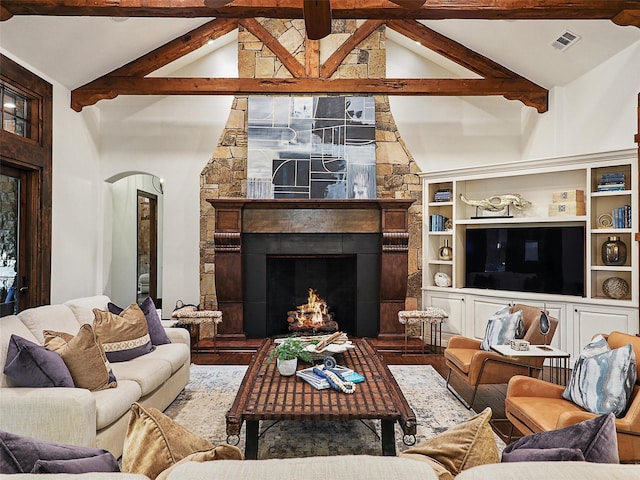 living area with visible vents, arched walkways, beamed ceiling, and a fireplace