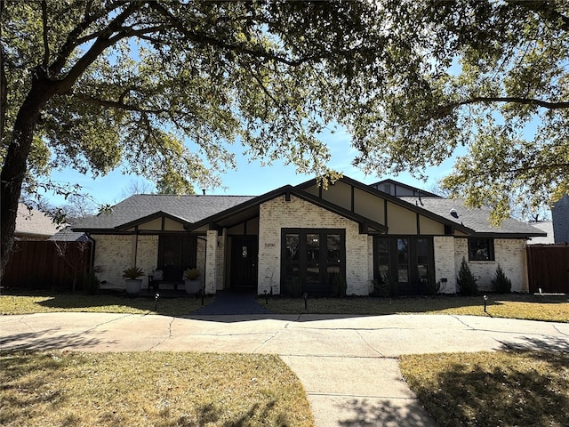 view of front of home featuring a front lawn, fence, brick siding, and roof with shingles