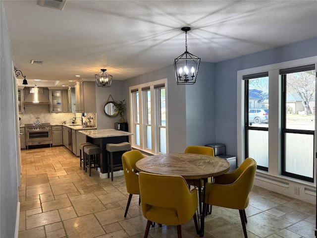 dining room featuring an inviting chandelier, visible vents, and stone tile flooring