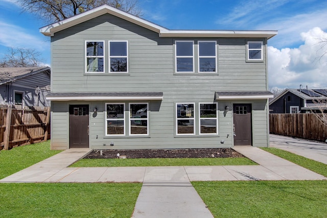 traditional-style home with a front yard and fence