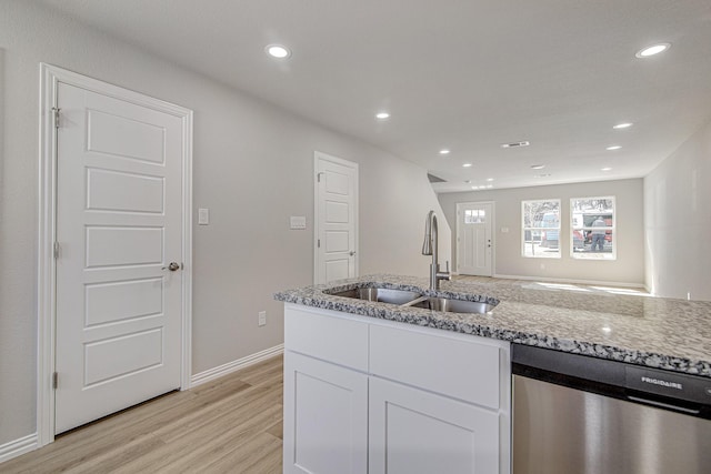 kitchen featuring a sink, stainless steel dishwasher, white cabinetry, light wood-style floors, and light stone countertops