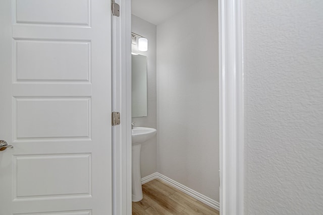 bathroom with baseboards, wood finished floors, and a textured wall