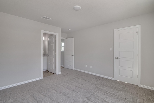 unfurnished bedroom featuring connected bathroom, baseboards, visible vents, and light carpet