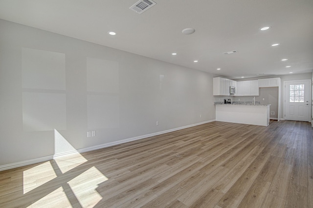 unfurnished living room with recessed lighting, light wood-style floors, visible vents, and baseboards