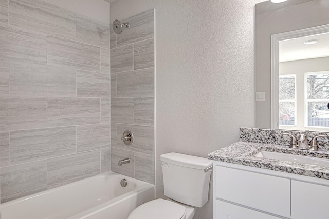 bathroom with vanity, toilet, a textured wall, and shower / bath combination