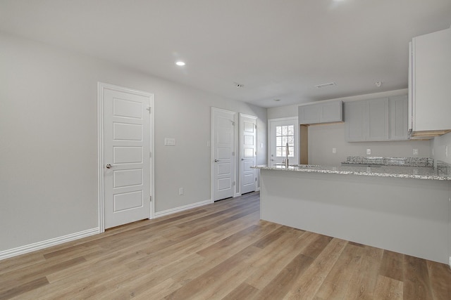 kitchen featuring baseboards, light stone countertops, recessed lighting, a peninsula, and light wood-style floors