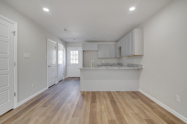 kitchen featuring recessed lighting, baseboards, a peninsula, and light wood-style flooring