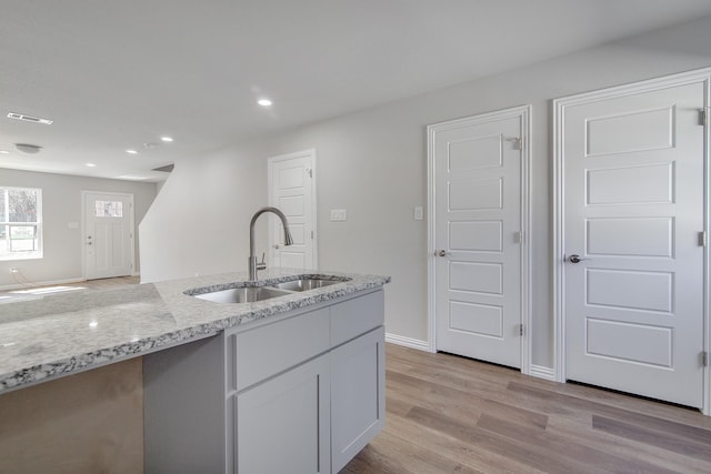 kitchen featuring light wood finished floors, visible vents, light stone countertops, recessed lighting, and a sink