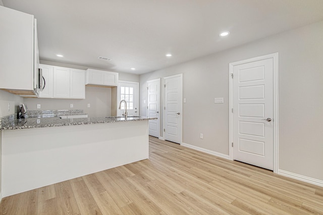 kitchen with visible vents, a sink, light wood-type flooring, light stone counters, and range