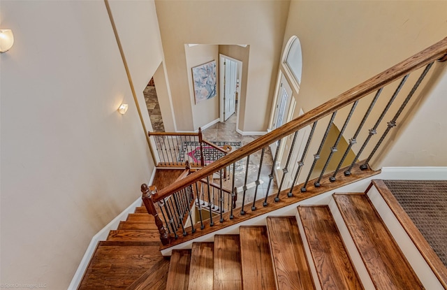 stairs with baseboards and a towering ceiling