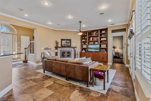 living room featuring a glass covered fireplace, recessed lighting, crown molding, and baseboards